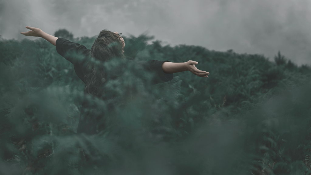 Imagen de cabecera blog The Green Vector, compuesta por una mujer en el bosque con los brazos abiertos disfrutando del paisaje.